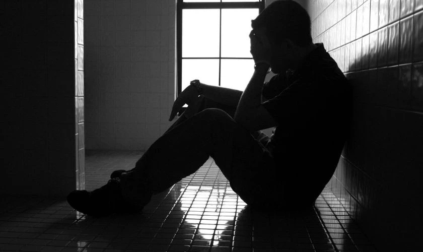 Ảnh buồn nam lẻ loi, chàng trai ngồi một mình bên cửa sổ với vẻ mặt suy tư