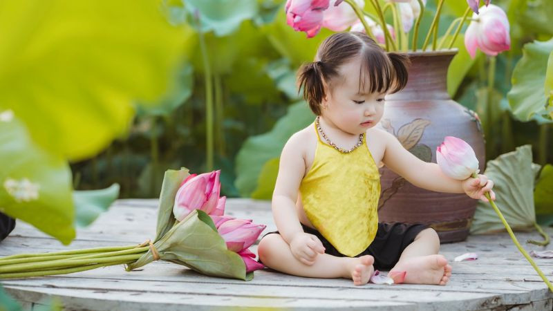 Ảnh em bé cute bên cạnh những bông hoa nhỏ xinh