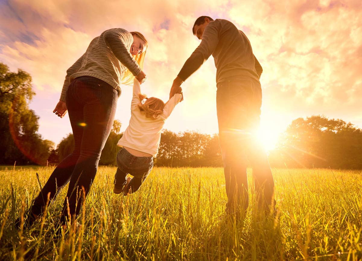 Ảnh gia đình 3 người đang vui đùa trên bãi cỏ xanh mướt