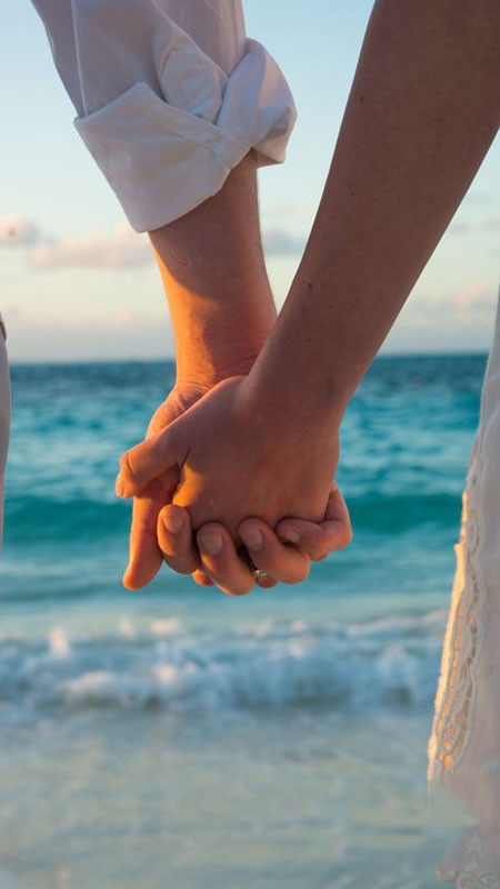 Ảnh nắm tay với phông nền là bãi biển vắng và bầu trời xanh