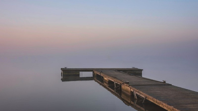 Ảnh phong cảnh buồn về buổi sáng sớm mờ sương trên mặt hồ phẳng lặng