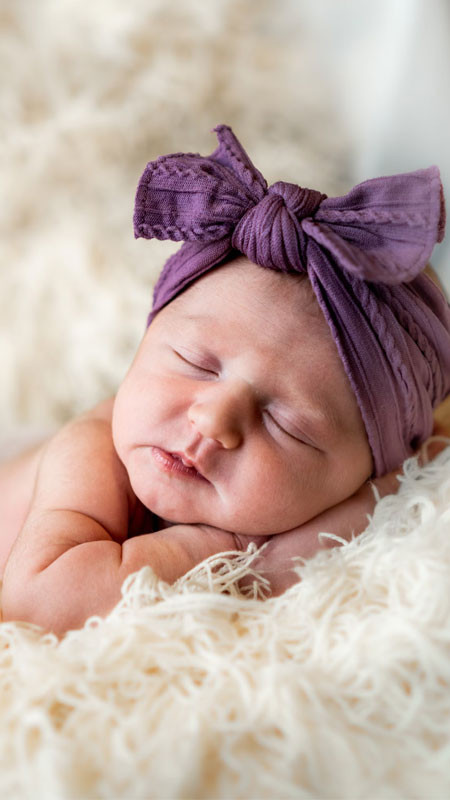 Bé gái sơ sinh nằm ngửa và đội băng đô