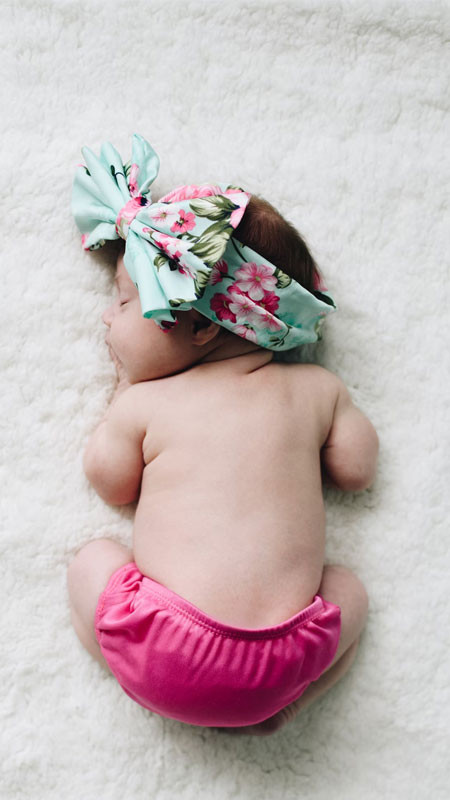 Bé gái sơ sinh ngủ trên nền vải xám