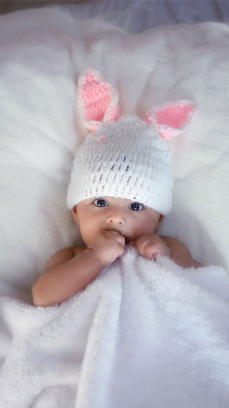 Bé gái sơ sinh quấn khăn và đội mũ đáng yêu