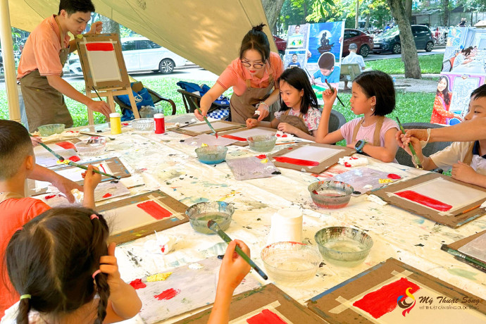 Bé trai đang say sưa với bức tranh vẽ cảnh hoàng hôn