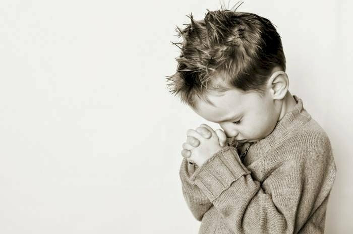 Bé trai ngồi khoanh tay cầu bình an cho người thân