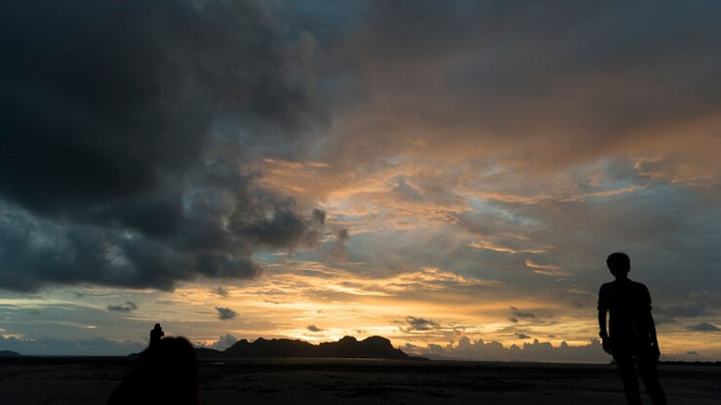 Bờ hồ phẳng lặng phản chiếu bầu trời nhiều mây xám