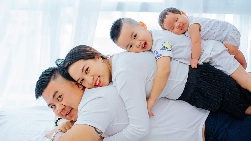 Bố mẹ và hai con trai ngồi ôm nhau trên sàn gỗ, đầy tình cảm