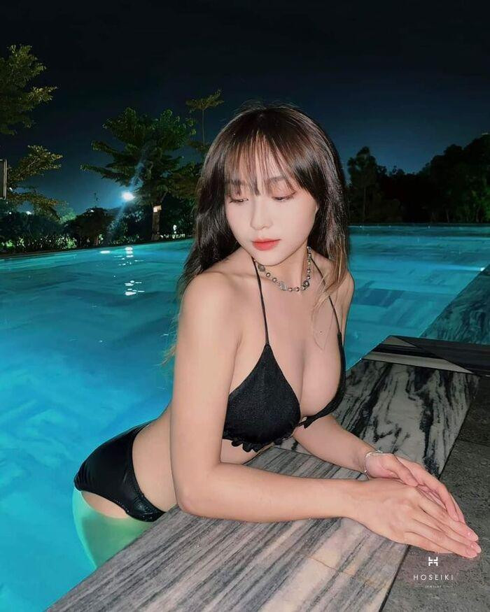 Bức ảnh chụp từ góc thấp lên, tập trung vào dáng đứng và trang phục, thể hiện sự quyến rũ