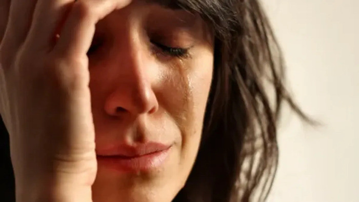 Cận cảnh gương mặt cô gái trẻ với nước mắt rơi, ánh mắt buồn bã