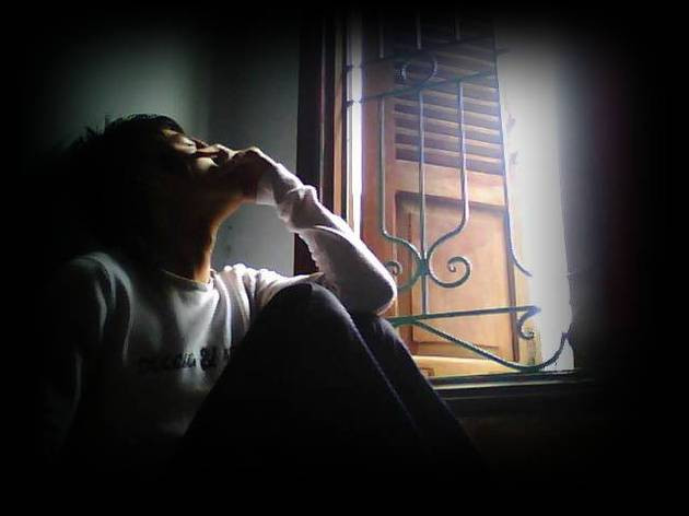 Chàng trai ngồi lặng lẽ bên cửa sổ, thể hiện sự cô lập hoặc nỗi buồn