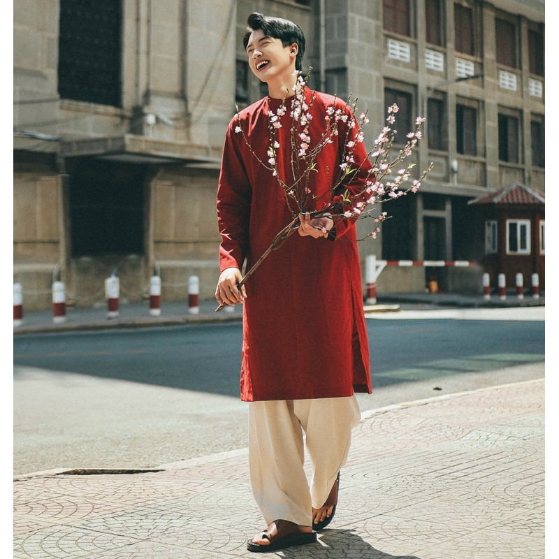 Chàng trai trẻ Việt Nam mặc áo dài truyền thống bên cành đào