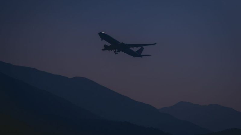 Chiếc máy bay phản lực nhỏ hơn đang cất cánh, nhìn từ xa với ánh đèn vàng rực trên nền trời đêm