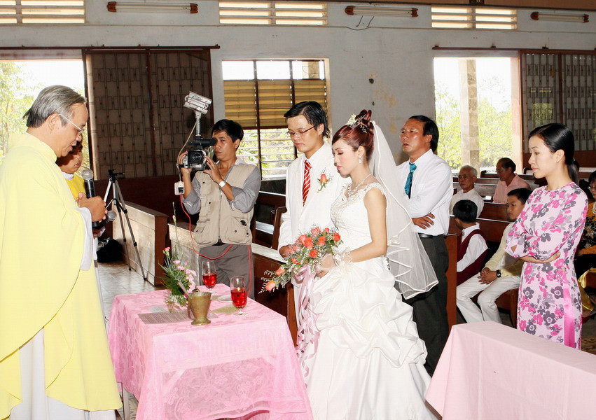 Cô dâu chú rể Công giáo cầu nguyện trước bàn thờ trong lễ cưới
