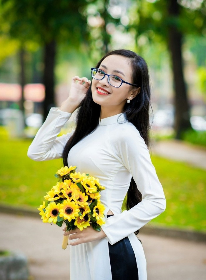 Cô gái mặc áo dài truyền thống duyên dáng bên cành hoa