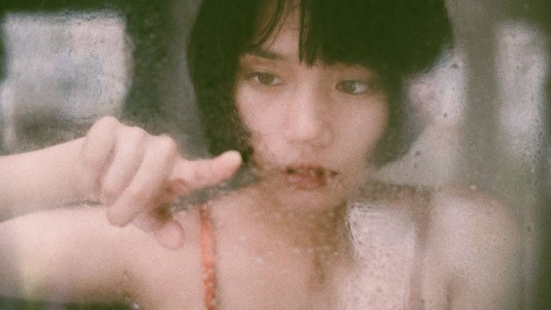 Cô gái nhìn qua cửa kính mờ sương, ánh mắt thẫn thờ thể hiện nỗi cô đơn sâu lắng