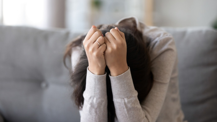 Cô gái trẻ gục mặt xuống bàn tay, thể hiện sự đau khổ