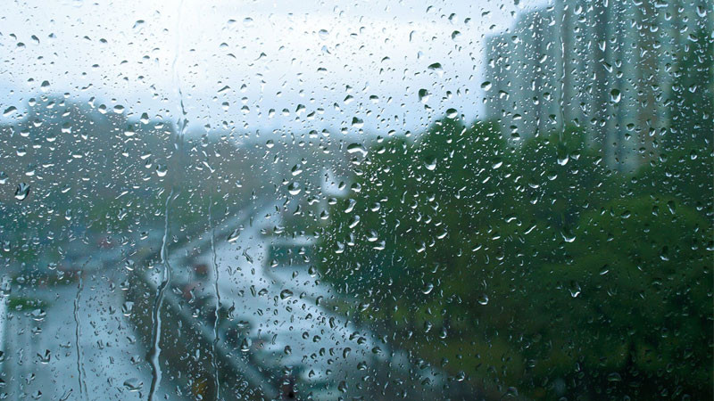 Cửa sổ với những giọt mưa trên kính và bầu trời xám mờ phía ngoài