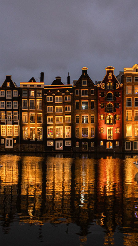 Dãy nhà cổ kính và kênh đào đặc trưng ở Amsterdam, một khung cảnh ảnh đường phố thanh bình.