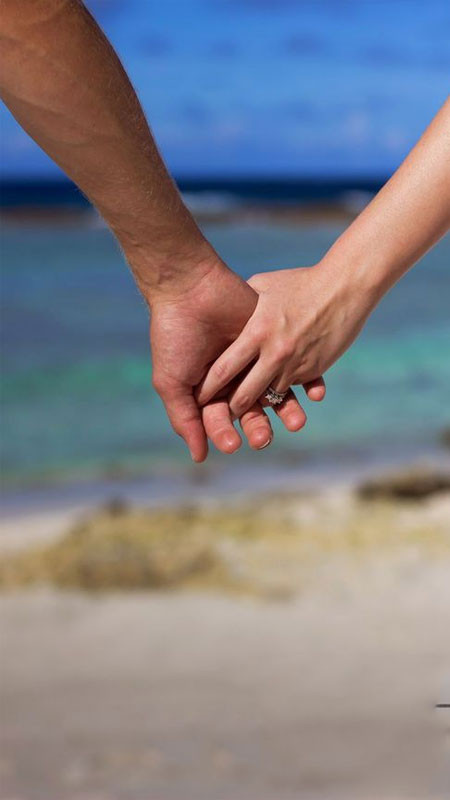 Đôi bàn tay nắm chặt bước chân trên cát hướng ra biển