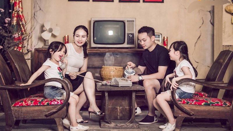 Gia đình 3 người mặc áo dài, ngồi trên ghế sofa chụp ảnh Tết