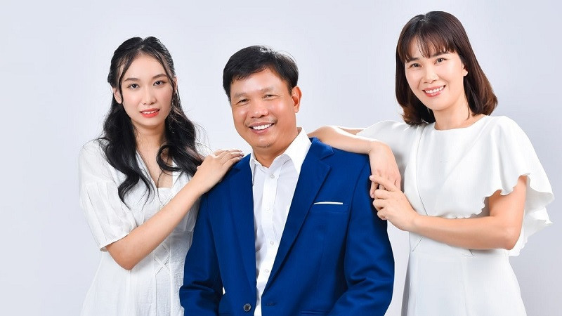 Gia đình 3 người mặc áo vàng rực rỡ ngồi chụp ảnh trong vườn hoa