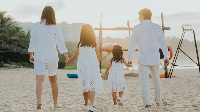 Gia đình 4 người mặc áo trắng, quần jean đơn giản, tạo dáng tự nhiên