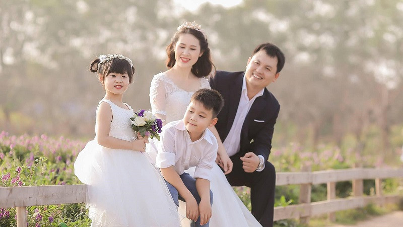 Gia đình 4 người mặc đồ đôi sọc ngang, ngồi trên nền trắng