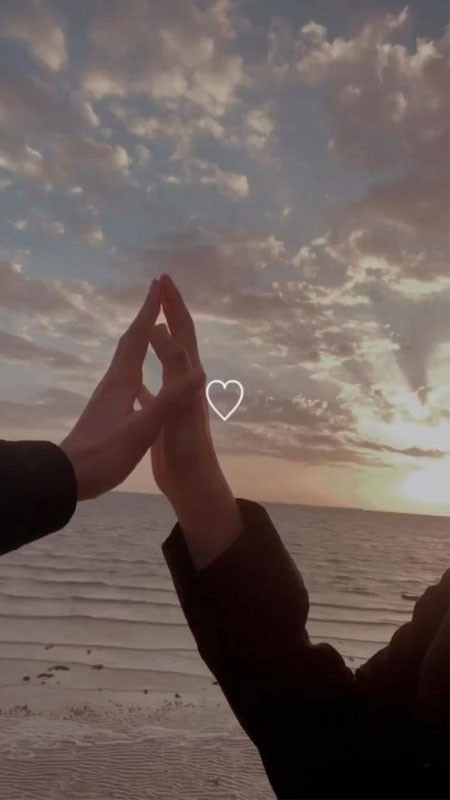 Góc chụp cận cảnh đôi bàn tay nắm lấy nhau trên bãi biển cát vàng