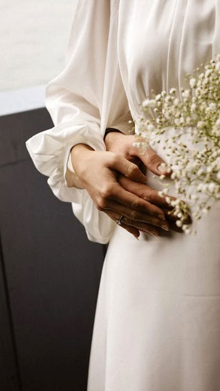 Góc chụp thấp làm nổi bật đôi bàn tay nắm chặt và nhẫn trên ngón áp út