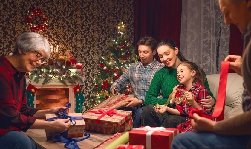 Hình ảnh bố mẹ và con cái ngồi cạnh cây thông Noel và những món quà