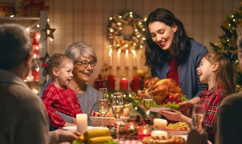 Hình ảnh các thành viên gia đình đang vui vẻ trò chuyện bên bàn ăn Giáng sinh