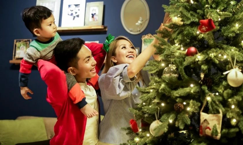 Hình ảnh các thành viên trong gia đình cùng nhau trang trí cây thông Noel