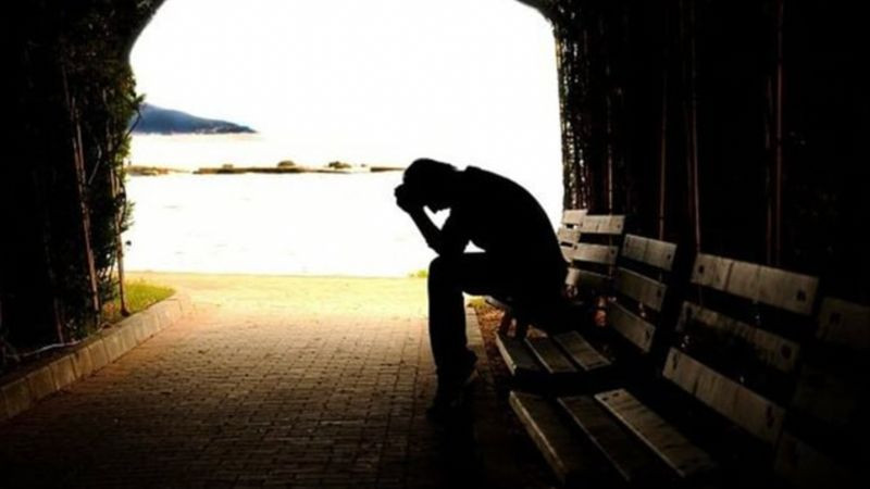 Hình ảnh cô đơn một người ngồi một mình trên băng ghế công viên giữa nhiều người khác