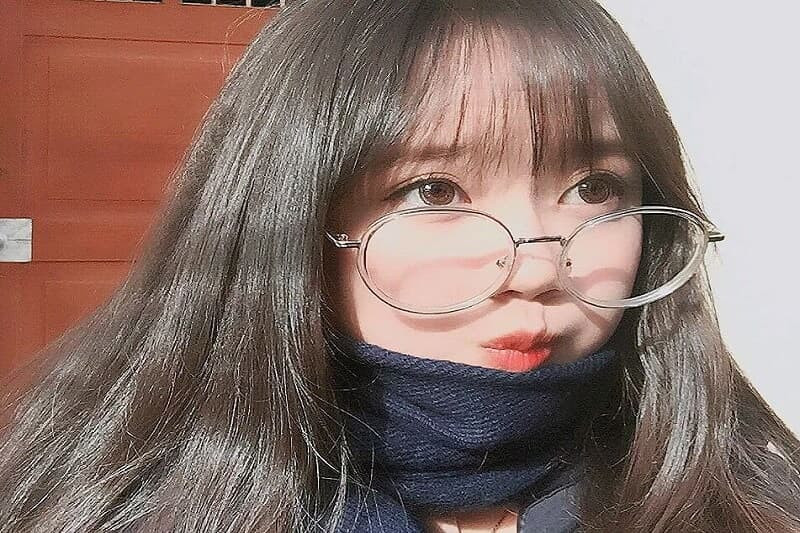 Hình ảnh con gái đeo kính ngồi bên cửa sổ