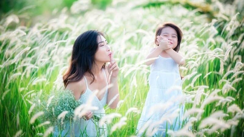 Hình ảnh mẹ và con gái đi dạo trên bãi biển lúc hoàng hôn, tạo nên khung cảnh lãng mạn.