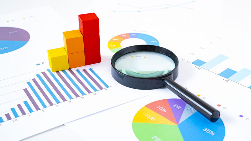 Hình ảnh minh họa nghiên cứu thị trường với biểu đồ và nhóm người phân tích dữ liệu, nhấn mạnh tầm quan trọng của việc hiểu khách hàng và đối thủ khi khởi nghiệp