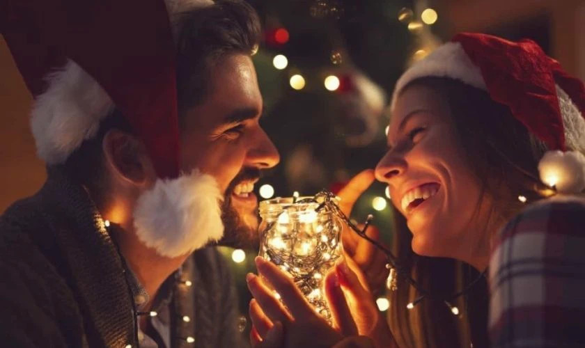 Hình ảnh một cặp đôi đang nắm tay nhau đi dưới đường phố trang trí Giáng sinh