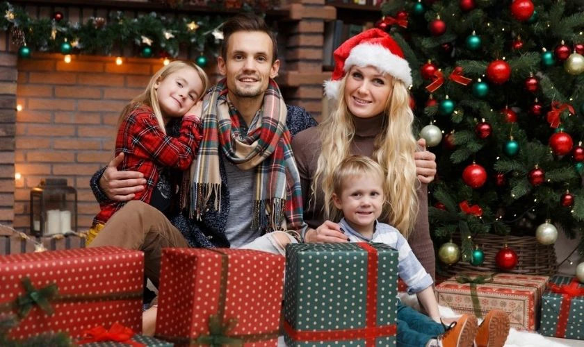 Hình ảnh một gia đình đang ngồi trước cây thông Noel