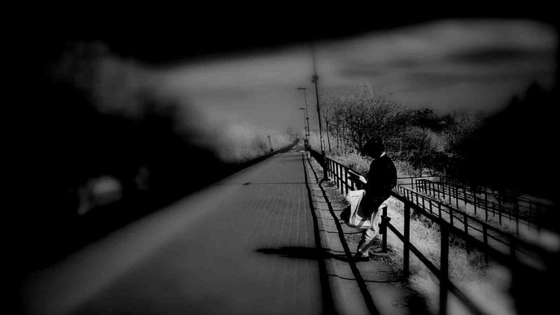 Hình ảnh một người đơn độc bước đi bên đường ray, gợi cảm giác lạc lõng và hành trình