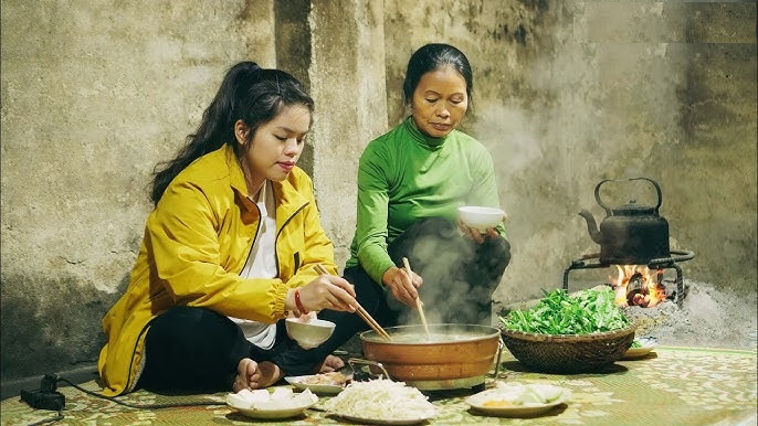 Hình ảnh người bà đang cặm cụi chuẩn bị bữa cơm đơn sơ bên bếp lửa