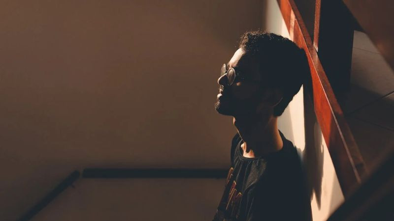 Hình ảnh người ngồi trong góc tối, thể hiện sự cô đơn và ẩn mình