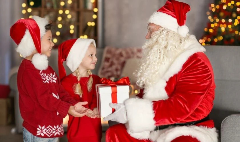 Hình ảnh ông già Noel đang trao hộp quà cho một bàn tay nhỏ