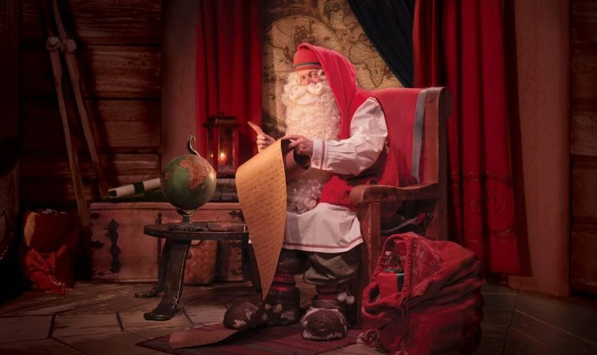 Hình ảnh ông già Noel đeo kính đang chăm chú viết trên một cuộn giấy