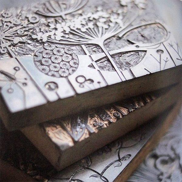 Họa sĩ sáng tác tranh in tập trung làm việc trên bản khắc kim loại để tạo tác phẩm nghệ thuật đồ họa.