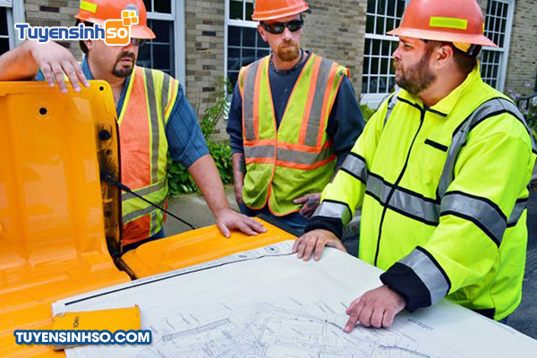 Kỹ sư quản lý xây dựng làm việc tại văn phòng công trường, kiểm tra hồ sơ dự án