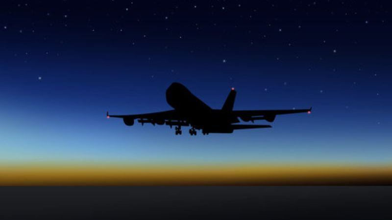 Máy bay đang bay lên cao sau khi cất cánh đêm, đèn trên thân máy bay tạo điểm nhấn trong bóng tối