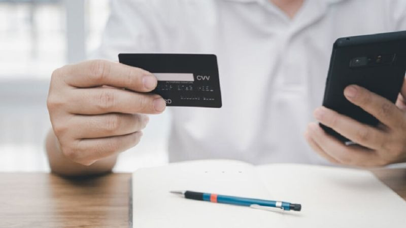 Một bàn tay đang ký tên vào dải chữ ký màu trắng ở mặt sau thẻ, biện pháp giúp nhân viên cửa hàng đối chiếu chữ ký khi thanh toán trực tiếp.