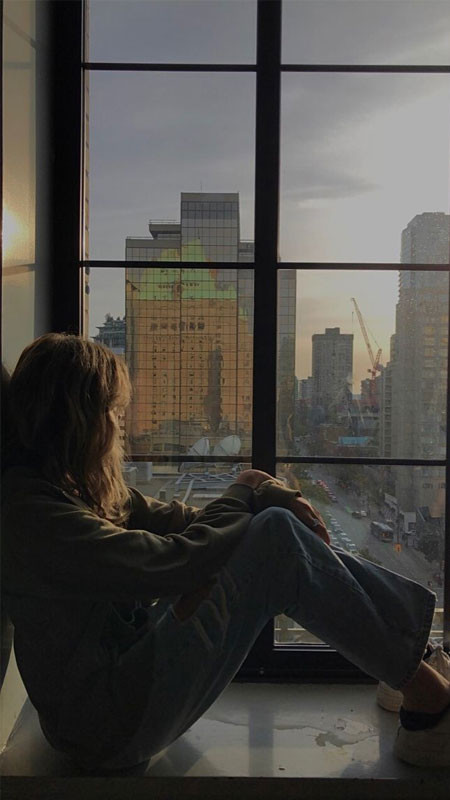 Một cô gái cúi đầu buồn bã bên cửa sổ, biểu tượng của nỗi cô đơn