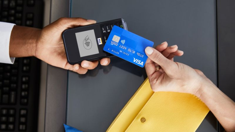 Một người đang dùng vật nhọn để làm mờ hoặc cào nhẹ dãy số mã CVV/CVC ở mặt sau thẻ, là một biện pháp vật lý để ngăn chặn việc nhìn trộm mã.